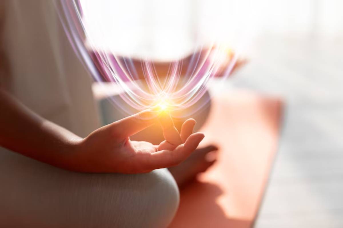 A hand in meditation creates a glowing light, symbolizing inner peace and energy, set against a soft, serene background.