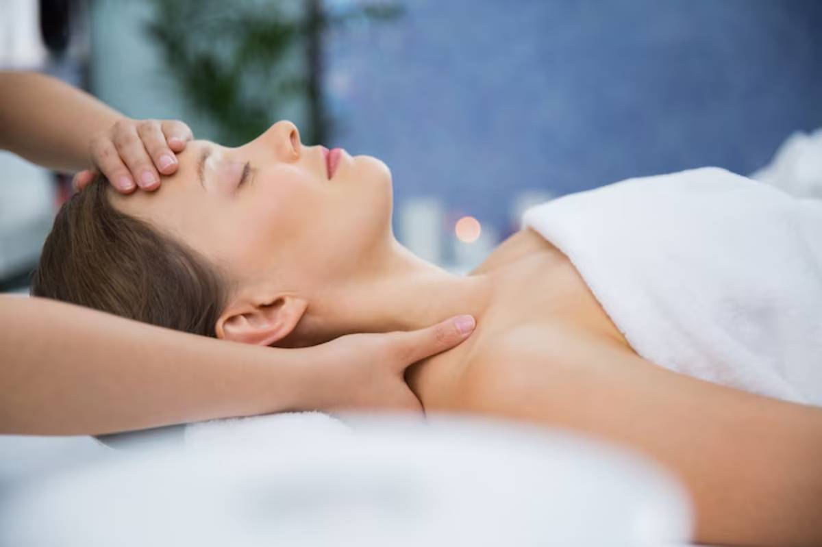 A person receiving a relaxing neck massage in a serene spa setting, draped in a white towel. Soft lighting enhances the tranquil atmosphere.