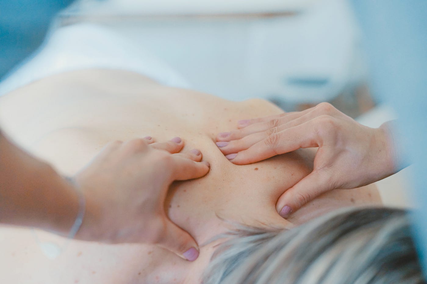 A therapist applies pressure to a client's back during a massage session, focusing on relaxation and relief.